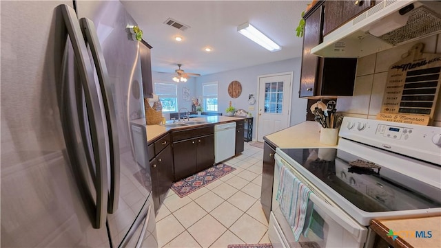 kitchen with dark brown cabinetry, sink, white appliances, light tile patterned floors, and ceiling fan