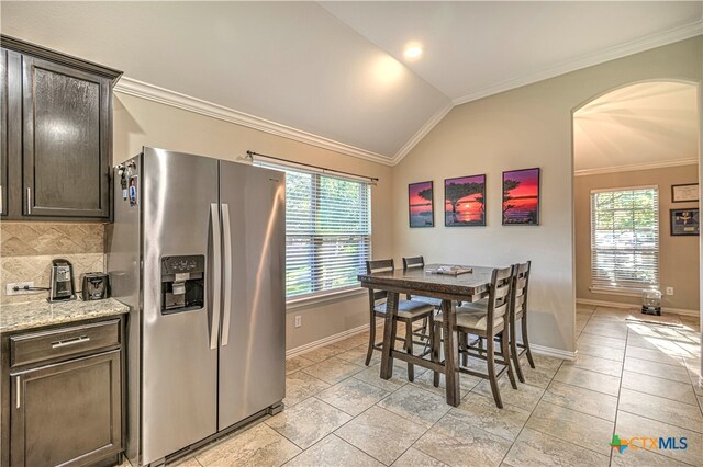 kitchen with stainless steel refrigerator with ice dispenser, dark brown cabinets, a healthy amount of sunlight, and lofted ceiling