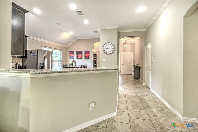 kitchen with light stone counters, ornamental molding, stainless steel fridge with ice dispenser, vaulted ceiling, and kitchen peninsula