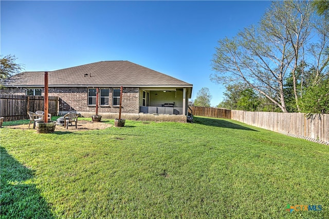 rear view of property with a yard, a fire pit, and a patio area