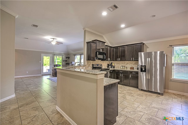 kitchen with stainless steel appliances, a healthy amount of sunlight, vaulted ceiling, and light stone countertops