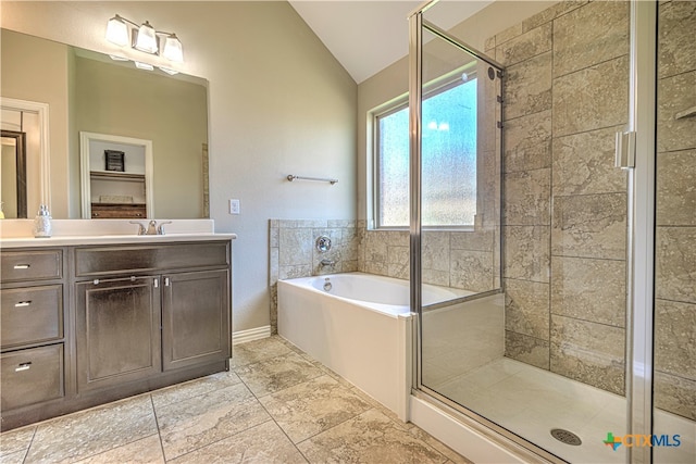 bathroom featuring independent shower and bath, vanity, and vaulted ceiling