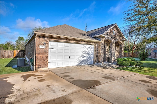 view of front of house featuring a garage, a front yard, and central AC