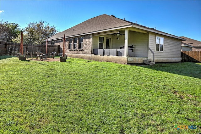 rear view of house featuring ceiling fan and a yard