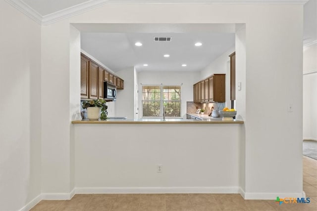 7778 Little Deer Trl, Georgetown, TX 78628 - kitchen featuring light tile patterned floors, baseboards, visible vents, backsplash, and light countertops
