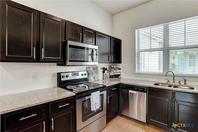 2400 Louis Henna Blvd Unit 305, Round Rock, TX 78664 - kitchen featuring light stone countertops, a sink, light wood finished floors, appliances with stainless steel finishes, and backsplash