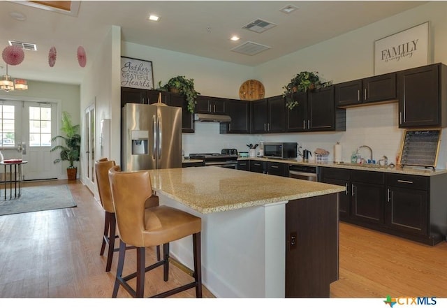 2400 Louis Henna Blvd Unit 305, Round Rock, TX 78664 - kitchen with backsplash, light wood-type flooring, a sink, under cabinet range hood, and stainless steel appliances