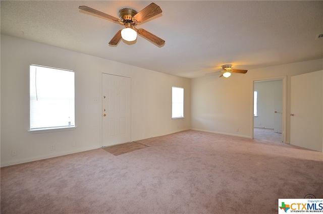 carpeted spare room featuring a textured ceiling, a healthy amount of sunlight, and ceiling fan