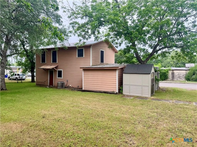 503 Dunn St, Yoakum, TX 77995 - back of house featuring a yard, central air condition unit, a storage unit, and an outbuilding