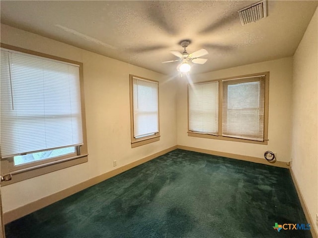 503 Dunn St, Yoakum, TX 77995 - empty room with a textured ceiling, dark colored carpet, visible vents, baseboards, and a ceiling fan