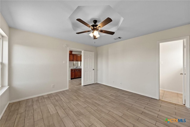 empty room with ceiling fan, sink, and light wood-type flooring