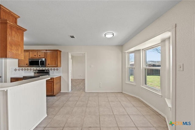 kitchen featuring appliances with stainless steel finishes, light tile patterned floors, and decorative backsplash