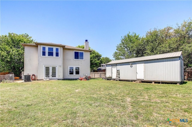 back of property with a chimney, fence, a yard, and french doors