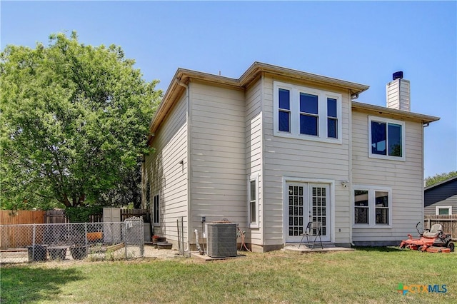 back of property featuring french doors, central AC, a chimney, fence, and a lawn