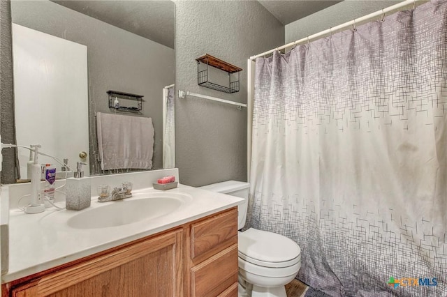 full bath featuring toilet, a textured wall, vanity, and a shower with shower curtain