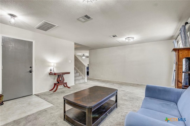 carpeted living area with a textured ceiling, stairway, and visible vents