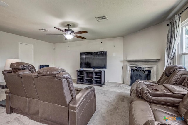 living room with ceiling fan, carpet floors, visible vents, and a fireplace