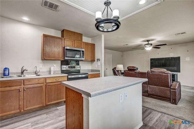 kitchen featuring stainless steel appliances, a sink, light wood-type flooring, visible vents, and light countertops