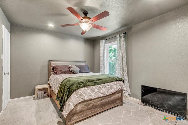 bedroom with a textured wall, a ceiling fan, and baseboards