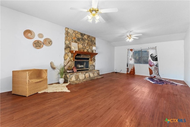 living area with a stone fireplace, wood finished floors, baseboards, and ceiling fan