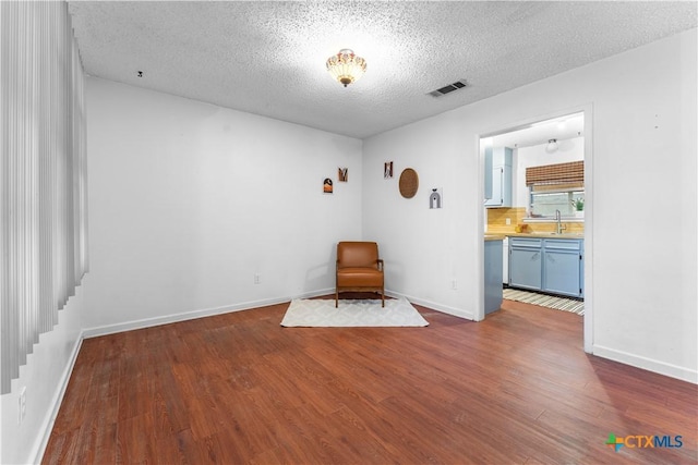 unfurnished room featuring baseboards, dark wood-style floors, visible vents, and a textured ceiling