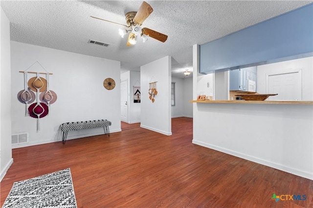 living room with visible vents, a textured ceiling, wood finished floors, and a ceiling fan