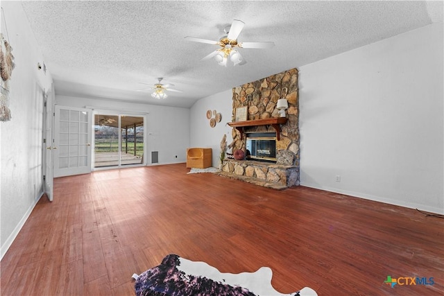 unfurnished living room with wood finished floors, baseboards, ceiling fan, a stone fireplace, and a textured ceiling