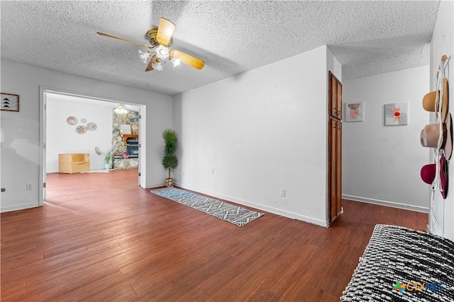 empty room featuring a textured ceiling, wood finished floors, baseboards, and ceiling fan