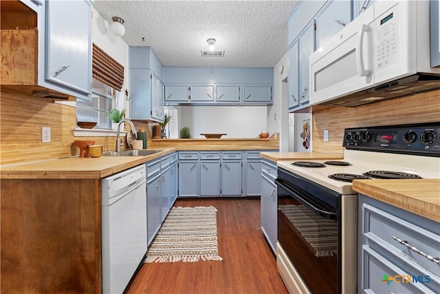 kitchen featuring visible vents, dark wood-type flooring, a sink, a textured ceiling, and white appliances