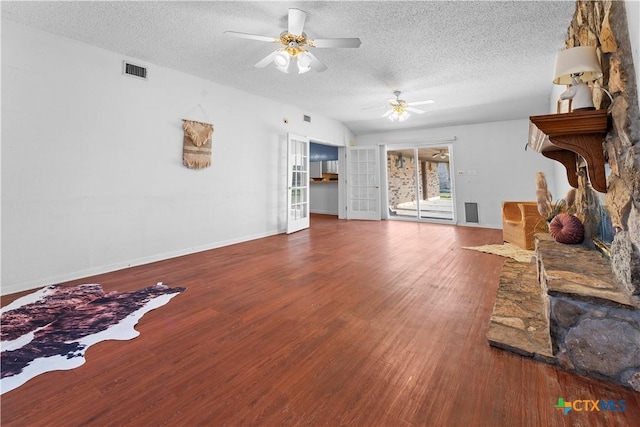 living area with wood finished floors, baseboards, a ceiling fan, visible vents, and a textured ceiling