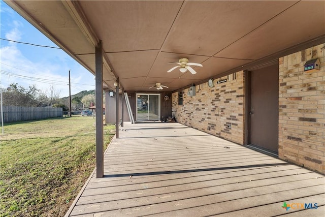 wooden terrace with a yard, ceiling fan, and fence