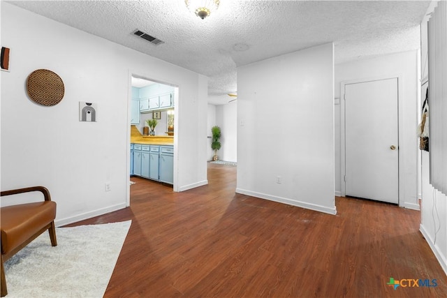 living area featuring baseboards, visible vents, dark wood-style flooring, and a textured ceiling