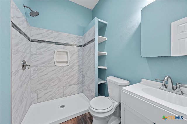 2212 Clay Ave, Waco, TX 76706 - full bathroom featuring toilet, vanity, tiled shower, and wood finished floors