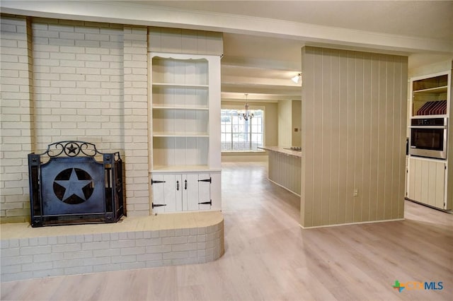 1705 Neuman St, Gonzales, TX 78629 - unfurnished living room with a chandelier, light wood-type flooring, and a fireplace