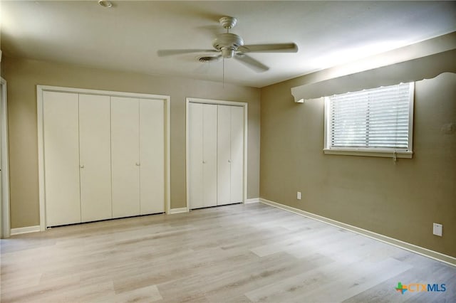 1705 Neuman St, Gonzales, TX 78629 - unfurnished bedroom featuring multiple closets, light wood-type flooring, and a ceiling fan