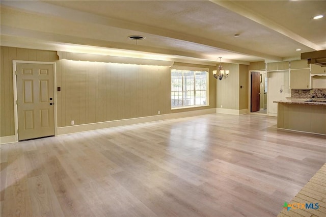 1705 Neuman St, Gonzales, TX 78629 - unfurnished living room with a chandelier, light wood-style floors, and beamed ceiling
