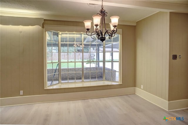 1705 Neuman St, Gonzales, TX 78629 - unfurnished dining area with wood finished floors, a chandelier, wooden walls, and crown molding