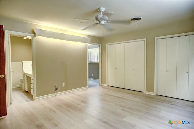 1705 Neuman St, Gonzales, TX 78629 - unfurnished bedroom featuring two closets, light wood-type flooring, ensuite bathroom, and a ceiling fan