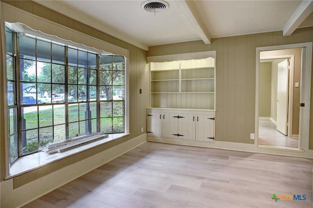 1705 Neuman St, Gonzales, TX 78629 - unfurnished dining area with beamed ceiling, plenty of natural light, light wood-style floors, and wood walls