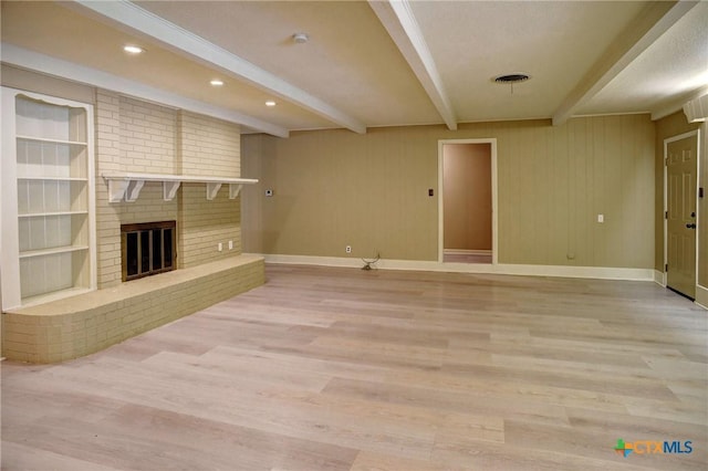 1705 Neuman St, Gonzales, TX 78629 - unfurnished living room featuring beamed ceiling, light wood-style flooring, a fireplace, recessed lighting, and built in shelves