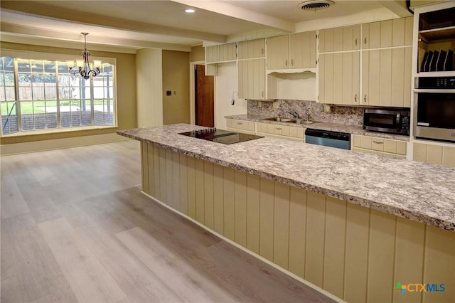 1705 Neuman St, Gonzales, TX 78629 - kitchen with black appliances, light wood finished floors, beamed ceiling, tasteful backsplash, and cream cabinets