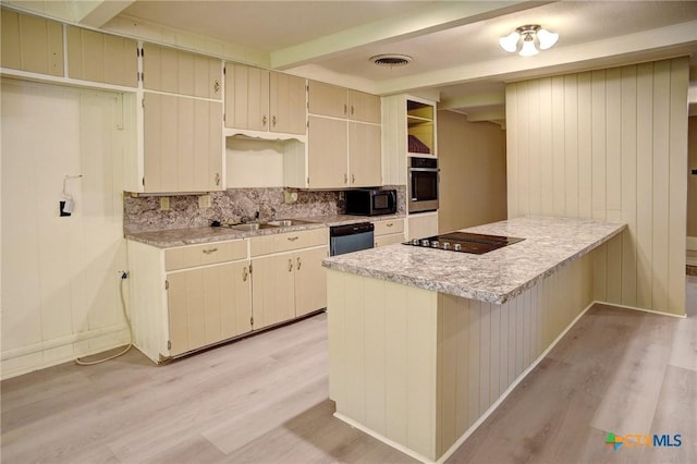 1705 Neuman St, Gonzales, TX 78629 - kitchen featuring black appliances, light wood-style flooring, light countertops, decorative backsplash, and a peninsula
