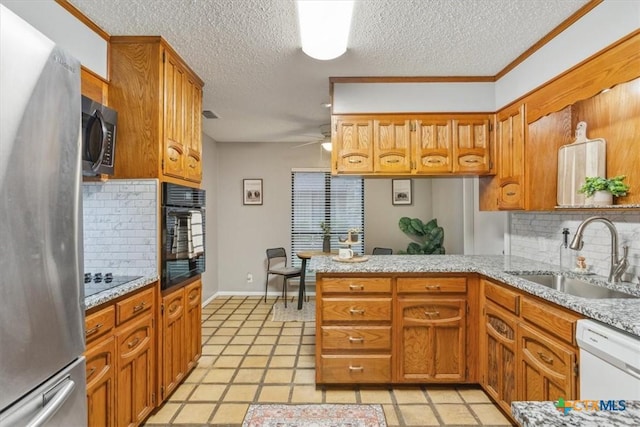 kitchen featuring black appliances, a sink, a peninsula, tasteful backsplash, and a textured ceiling