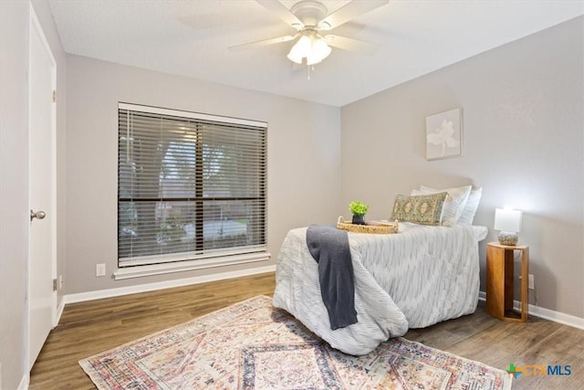 bedroom with wood finished floors, baseboards, and a ceiling fan
