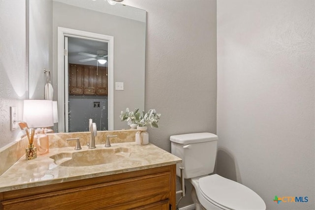 bathroom featuring vanity, toilet, ceiling fan, and a textured wall