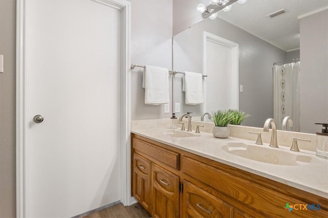 full bath featuring double vanity, wood finished floors, and crown molding