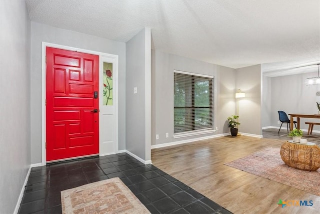 tiled foyer entrance featuring a textured ceiling and baseboards