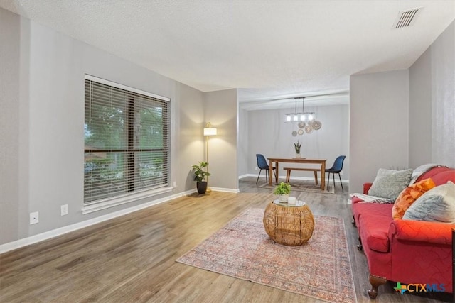living area with wood finished floors, a chandelier, and baseboards