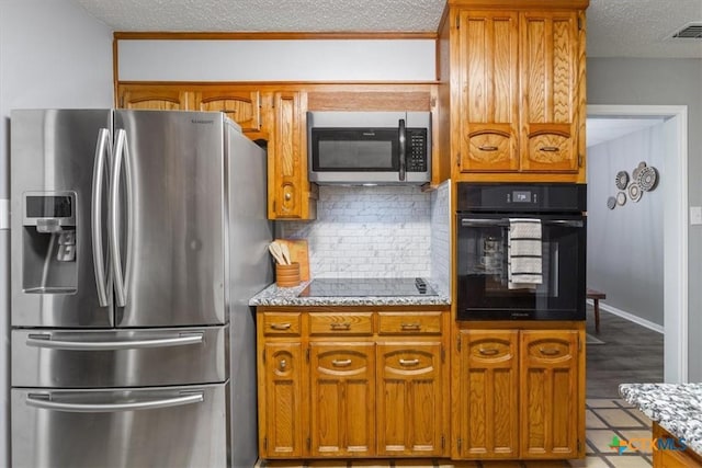 kitchen with black appliances, a textured ceiling, brown cabinets, tasteful backsplash, and light stone countertops