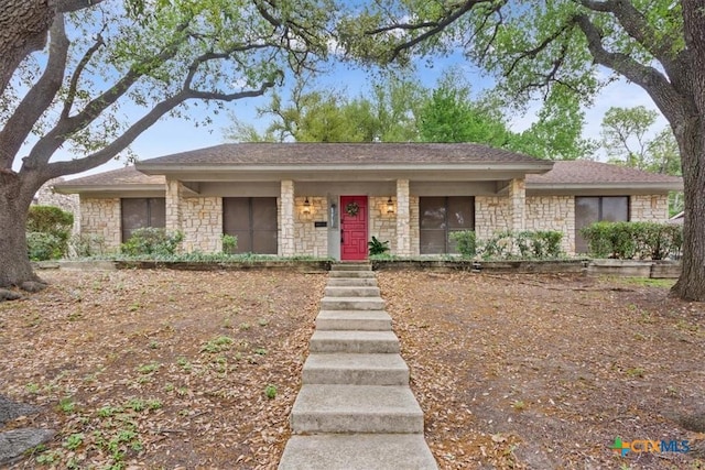 ranch-style house featuring stone siding and roof with shingles